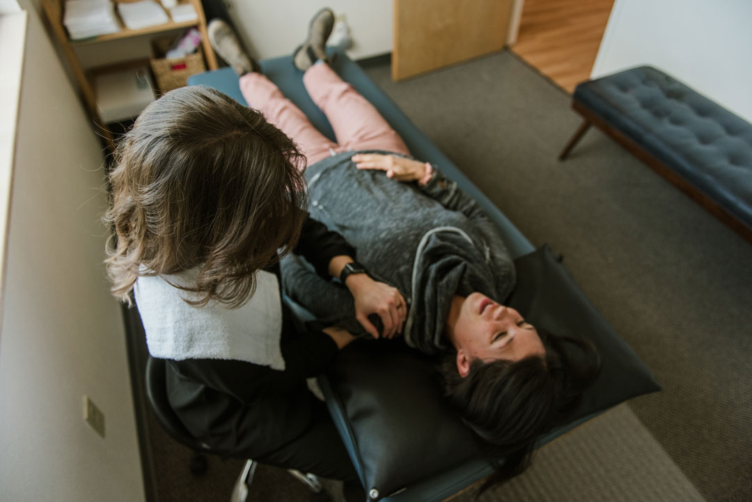 A closeup of Dr. Becca Murrer working with a patient on a physical therapy table