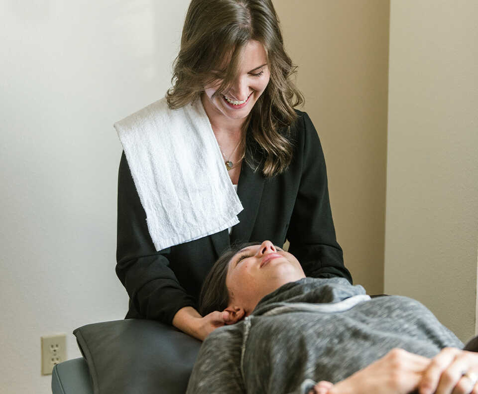 physical therapist smiling helping a patient